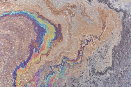 A marble texture of a rainbow spill of gasoline on a sidewalk in a puddle as a background.の写真素材