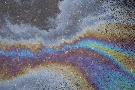 Abstract colored background of leaked gasoline on wet asphalt close-up.の写真素材