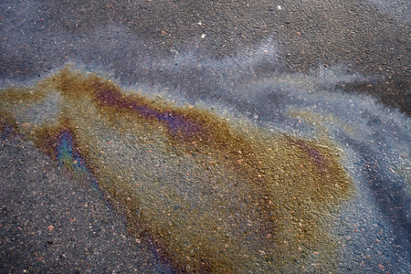Textured stain of fuel or oil on wet asphalt on a rainy day.の写真素材