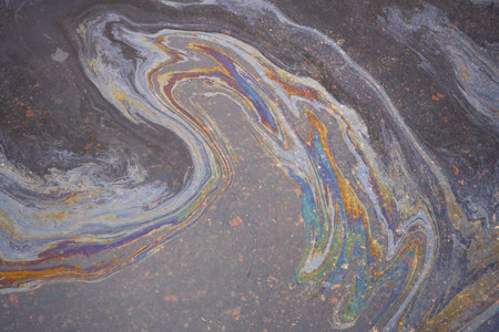 A marble texture of a rainbow spill of gasoline on a sidewalk in a puddle as a background.の写真素材