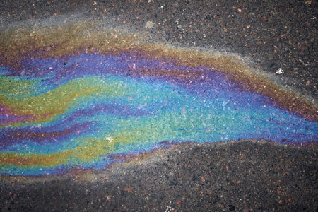 Spilled oil in a puddle on the road. Oil stains on wet pavement.の写真素材