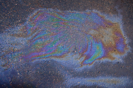Colored texture of oil products on the asphalt in the rain. Oil dripped from the car engine onto the roadの写真素材