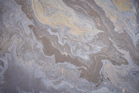 a marble texture of a rainbow spill of gasoline on a sidewalk in a puddle as a backgroundの写真素材