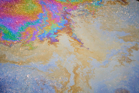 Petroleum fuel spilled on wet asphalt, abstract background.の写真素材