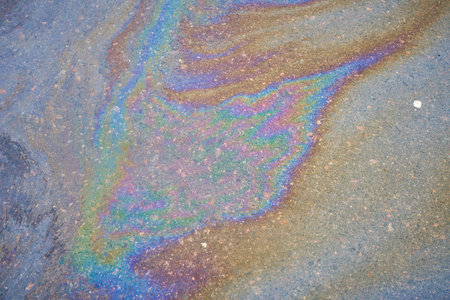 Petroleum fuel spilled on wet asphalt, abstract background.の写真素材
