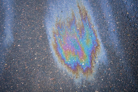 Background texture of an oil spill in the form of a rainbow stain on dark asphalt, parking.の写真素材