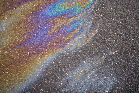 A puddle of spilled gasoline or oil product on the road. Environmental pollution conceptの写真素材