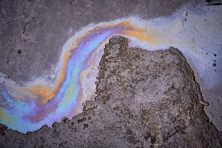 Leakage of oil or gasoline from under the car on the asphalt in the parking lot.の写真素材