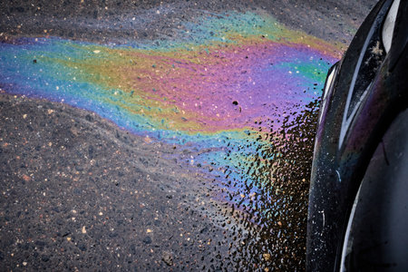 Gasoline and oil spill on wet asphalt in a parking lot near a hypermarket.の写真素材