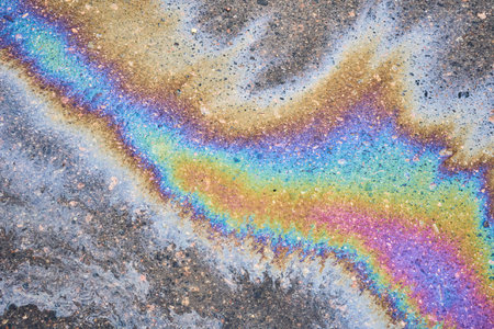 Textured stain of fuel or oil on wet asphalt on a rainy day. The concept of environmental pollution.の写真素材