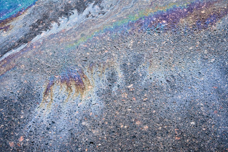Background texture of oil spill on dark asphalt, parking lot.