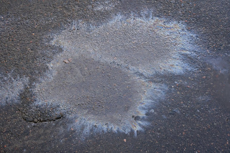 Oil stains on wet asphalt. Puddles are contaminated with multicolored streams of oilの写真素材