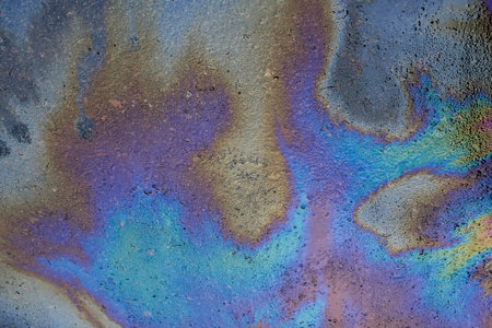 Textured stain of fuel or oil on wet asphalt on a rainy day. The concept of environmental pollution.の写真素材