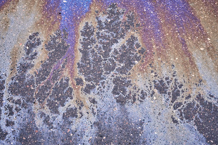 Vibrant oil slick spread across the asphalt road, showcasing a spectrum of colors