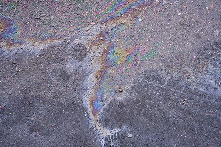 Swirling, shimmering oil stain on asphalt surface.の写真素材