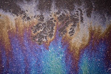 Gasoline or oil slick creating a rainbow chemical reaction on a wet asphalt road surface.の写真素材