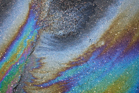 A sheen of fuel on a rainy street revealing the consequences of environmental neglectの写真素材