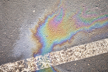 Wet asphalt of parking lot, showing motor oil or fuel spill, indicated by white lineの写真素材