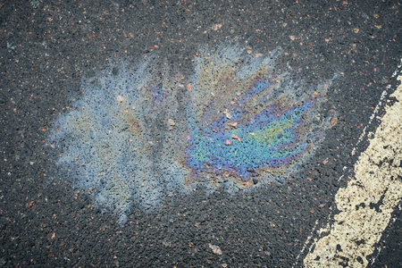 Damp surface in a parking spot, showing a fuel leak from a car, outlined with a white stripeの写真素材