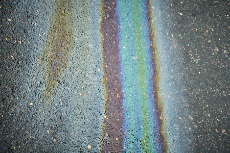 Oil Slick Creates Colorful Patterns on Asphalt Surface After Rain in Urban Settingの写真素材