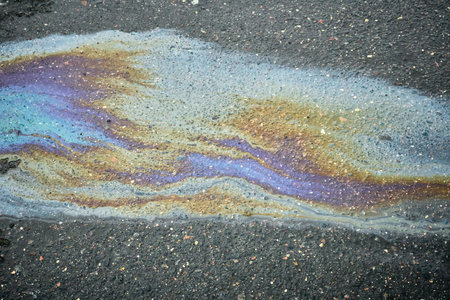 Oil Slick Creating a Colorful Pattern on Asphalt Surface After Rainfall in an Urban Areaの写真素材
