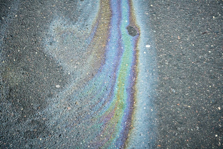 Colorful Oil Slick Patterns on Asphalt Near a Parking Lot During Daylight Hoursの写真素材
