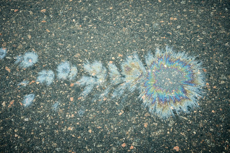Colorful Oil Spill Pattern on Asphalt Road Creates an Eye-Catching Visual Display During the Dayの写真素材