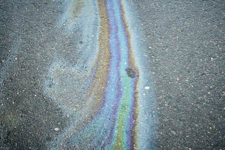 Colorful Oil Sheen on Pavement Creates Striking Visual Effect in Urban Environmentの写真素材