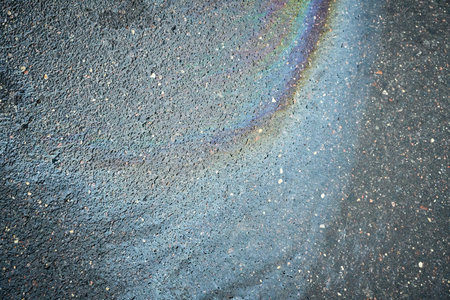 Colorful Oil Slick Creates Swirling Patterns on Urban Asphalt Surface After Recent Rainの写真素材