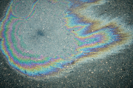 Colorful Oil Slick Patterns on Asphalt Surface After Rain From Nearby Vehicles and Urban Activities.の写真素材