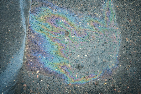 Colorful Oil Slick Reflecting Vibrant Hues on Wet Pavement After Rainfall in Urban Settingの写真素材