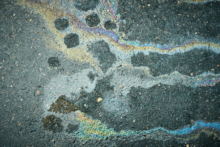 Colorful Oil Slick Forms Patterns on Wet Asphalt After Rainfall in an Urban Settingの写真素材