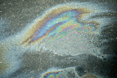 Colorful Oil Slick on Asphalt Creates Vibrant Patterns Under Natural Light in an Urban Environmentの写真素材