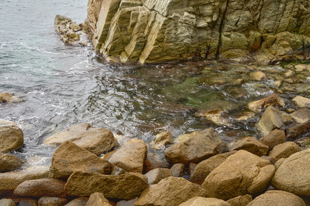 Rocky Shoreline With Clear Water and Tidal Movement at a Coastal Location During Cloudy Weatherの写真素材