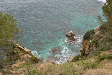 Rocky Coastline View Showcasing Tranquil Turquoise Waters and Natural Rock Formations Near a Forested Areaの写真素材