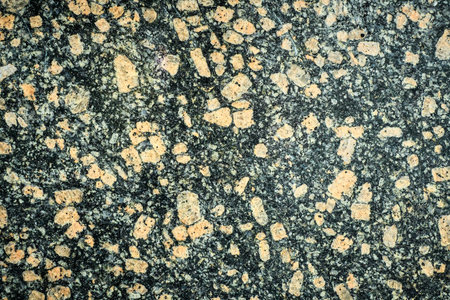 Unique Texture of Polished Granite With Flecks of Orange and Black in a Close-Up View Showcasing...