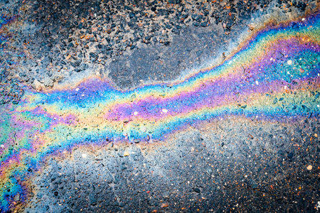 Iridescent oil or gasoline spill on a wet asphalt, viewed from above.の写真素材