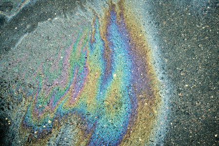 Gasoline or oil spill creating rainbow sheen on asphalt road surface.の写真素材