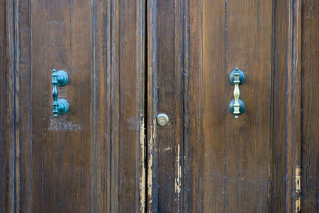 Distinctive Wooden Doors With Unique Handles in an Old Building Showcasing Craftsmanship and Historyの写真素材