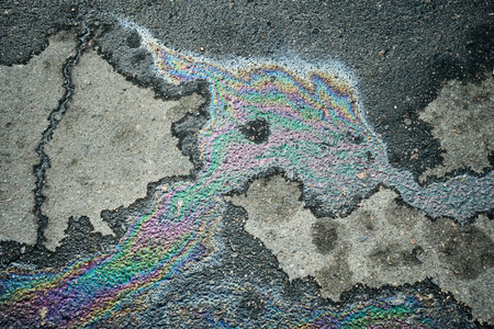 Iridescent oil spill creating abstract rainbow pattern on asphaltの写真素材