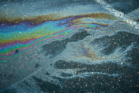 Oil spill creating vibrant psychedelic rainbow pollution on asphaltの写真素材
