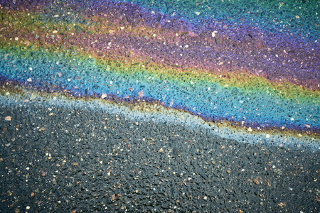 Iridescent oil slick creating abstract rainbow pattern on asphalt.の写真素材