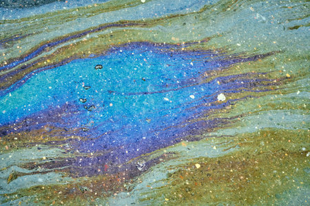 Oil spill on water forming a vibrant iridescent pattern, showing environmental pollution, chemical...