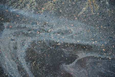 Iridescent oil slick creating colorful patterns on dark urban asphalt.