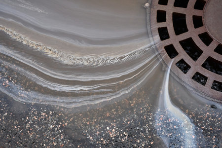 Water Flows Into a Drain With Visible Patterns on the Surface of the Water at a City Street.