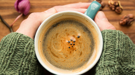 A men's hands are holding a cup of aromatic coffee. A cup of aromatic coffee stands on a wooden...