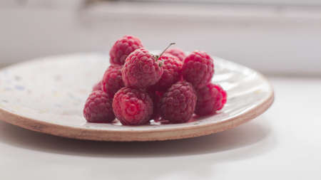 Ripe juicy raspberries lies on a plate.の写真素材