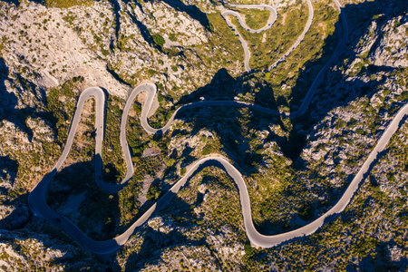Spectacular aerial view of famous Sa Calobra road through Mallorca's rugged Tramuntana mountains. Winding mountain pass with sharp turns, breathtaking scenery. Favorite destination for hikers, cycling enthusiasts.の写真素材
