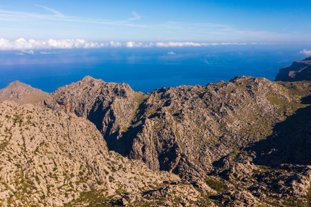 Stunning aerial view Tramuntana mountain range in Mallorca, with rugged peaks, deep blue Mediterranean Sea, soft clouds drifting above. Breathtaking natural landscape showing beauty islandの写真素材