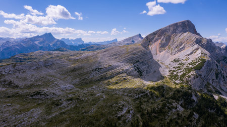 High rocks. Alps in Italy. South Tyrol. Dolomites. Green landscape with stones and green vegetation. Mountain landscape. Shooting from drone. Photo from a copter. Tourism.Blue cloudsの写真素材